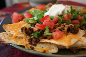 plate of chips with cheese, meat, tomatoes, and green onions