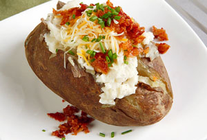 picture of a potato topped with bacon, cheese, and green onions