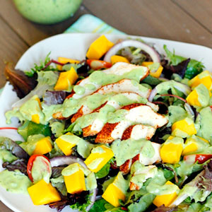 A large salad with fruit and grilled chicken