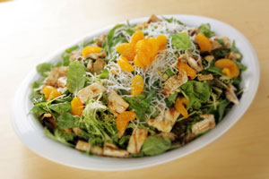 picture of a salad with mangos, chicken and asian food items